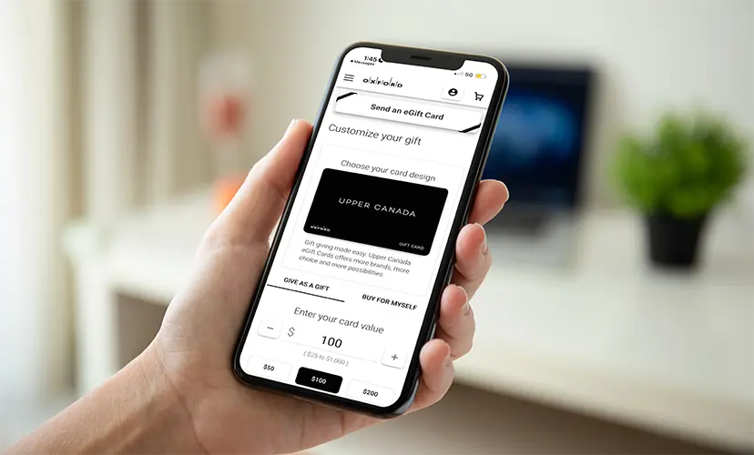 Hand holding a phone on the Upper Canada eGift card design and value screen
