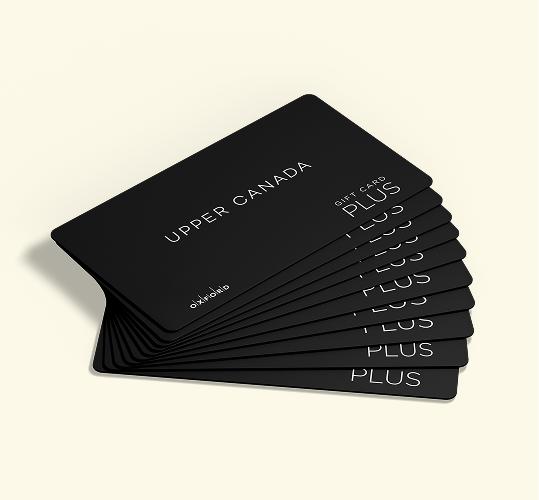 Fanned-out stack of black Upper Canada Plus gift cards on cream