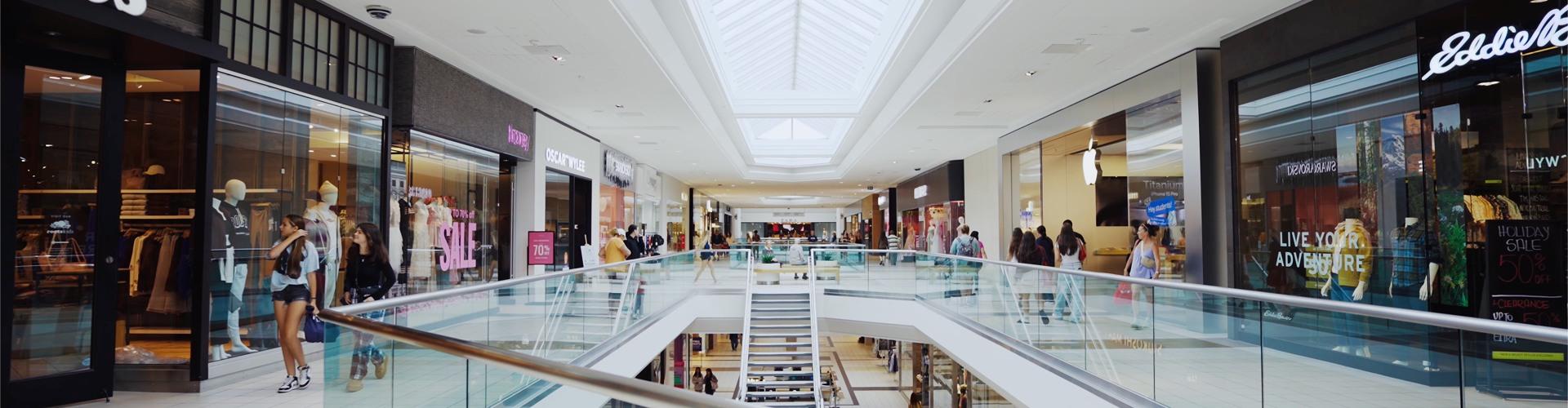 Two-level mall concourse under skylights with a central staircase and stores