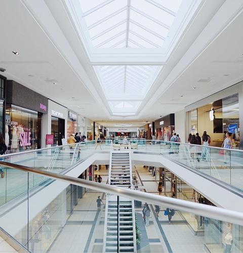 Two-level mall concourse under skylights with a central staircase and stores
