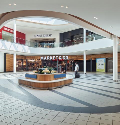 Mall atrium with a circular seating planter outside the Market & Co. food hall
