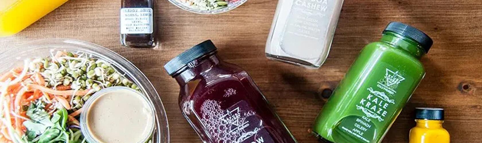 Cold-pressed juices and a fresh salad bowl arranged on a wooden table