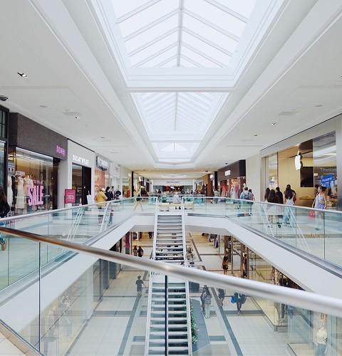 Two-level mall concourse under skylights with a central staircase and stores