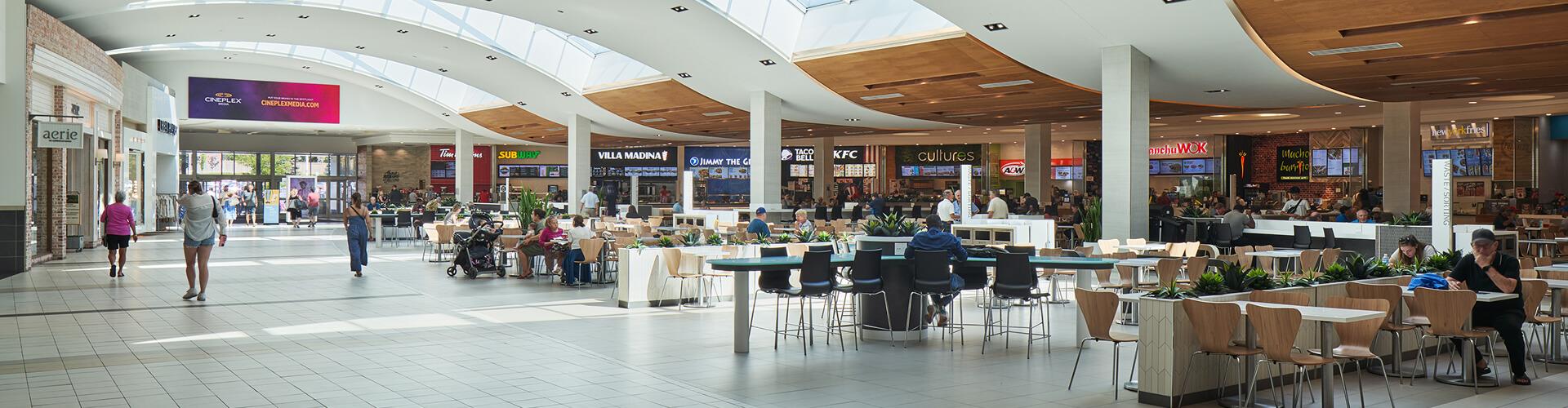 Busy mall food court under skylights with Villa Madina, KFC and A&W