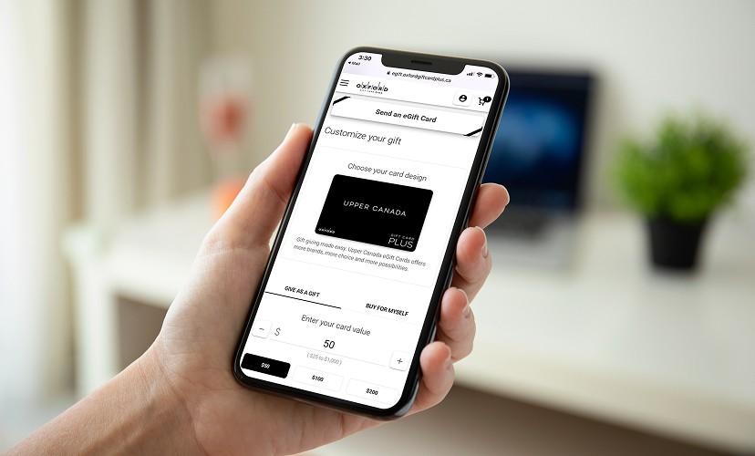 Hand holding a phone on the Upper Canada eGift card design and value screen