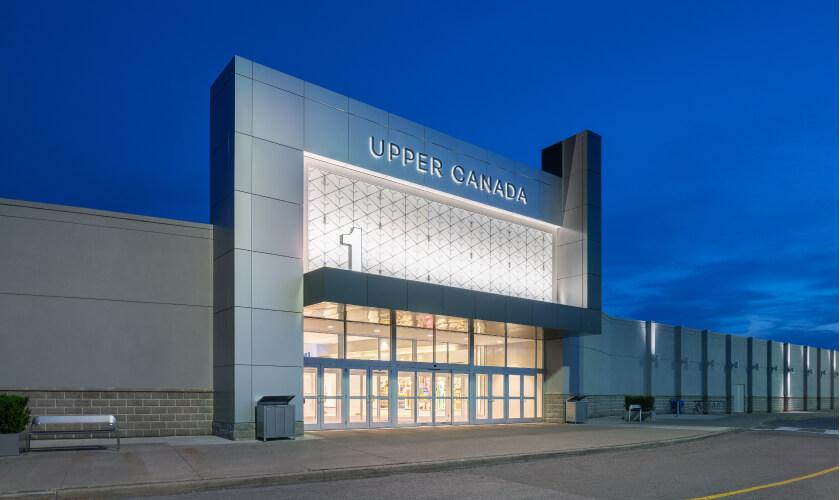Illuminated Upper Canada mall entrance and glass doors at dusk