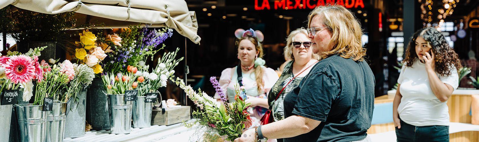 Shopper choosing fresh flowers at a market stall near La Mexicanada