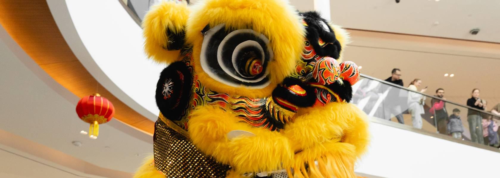 Yellow lion dance costume performing at a Lunar New Year event in the mall