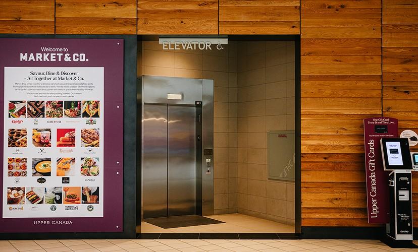 Elevator and Market & Co. welcome sign beside an Upper Canada gift card kiosk