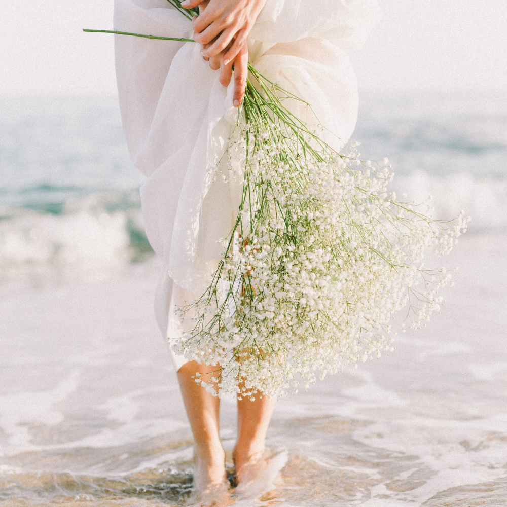 Bride holding a bouquet along the beach