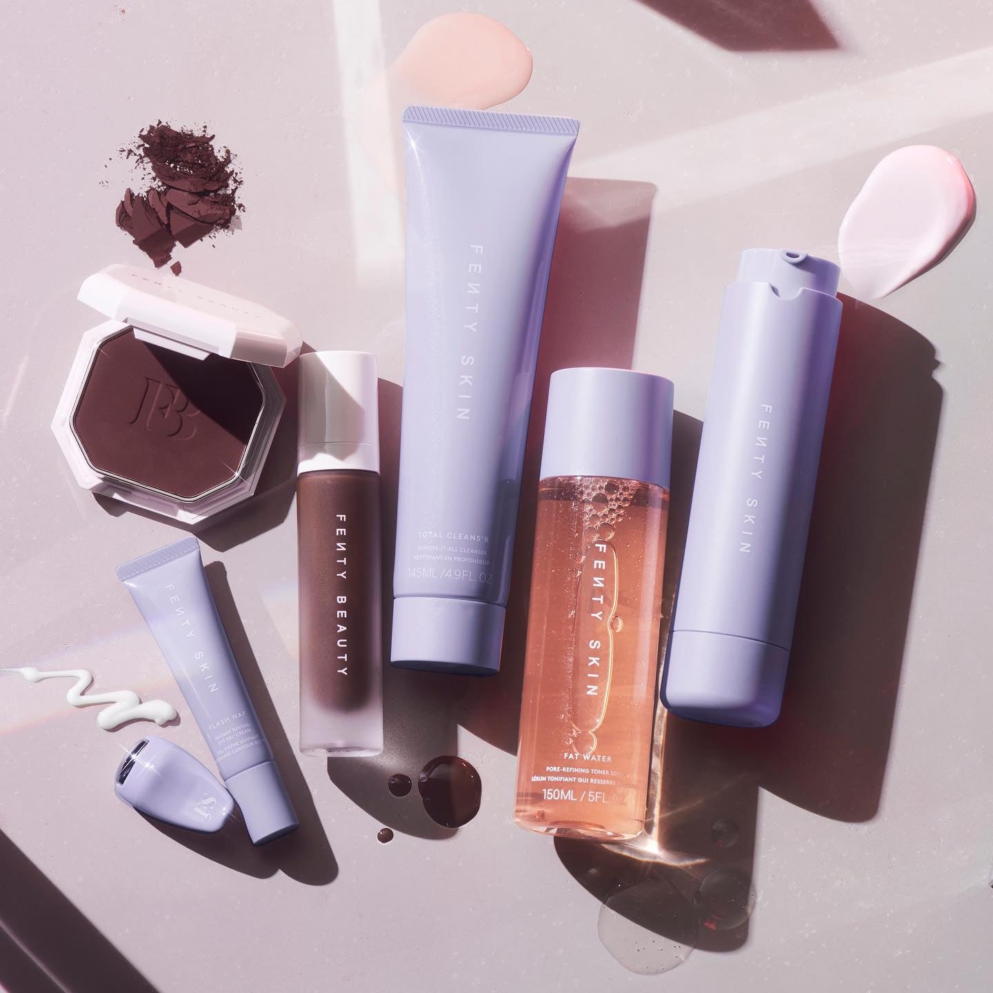 Various Fenty Beauty and Fenty Skin products are flat laid on a light background.