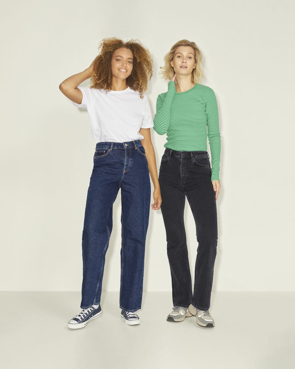 Two women wearing denim with a white and green shirt
