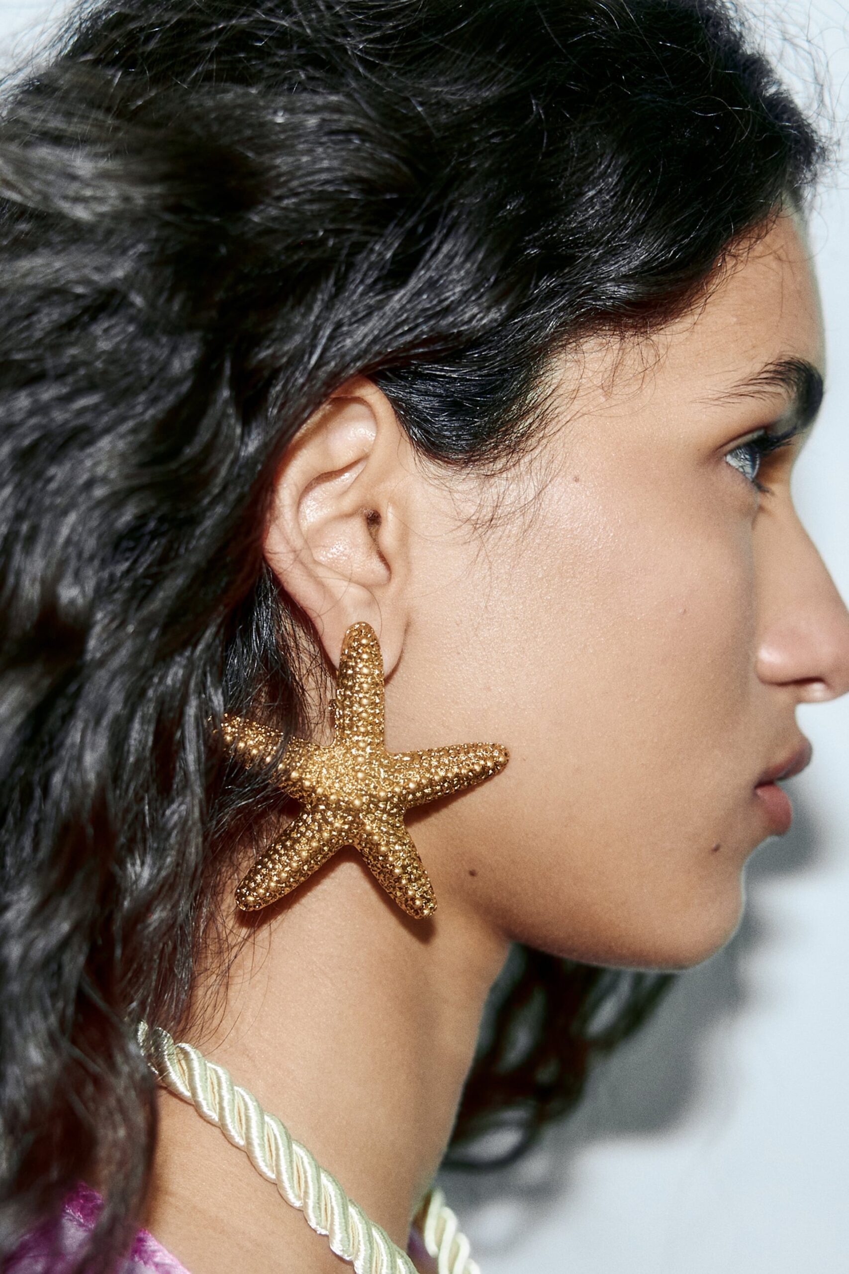 close-up image of a woman's profile. she is wearing large starfish earrings