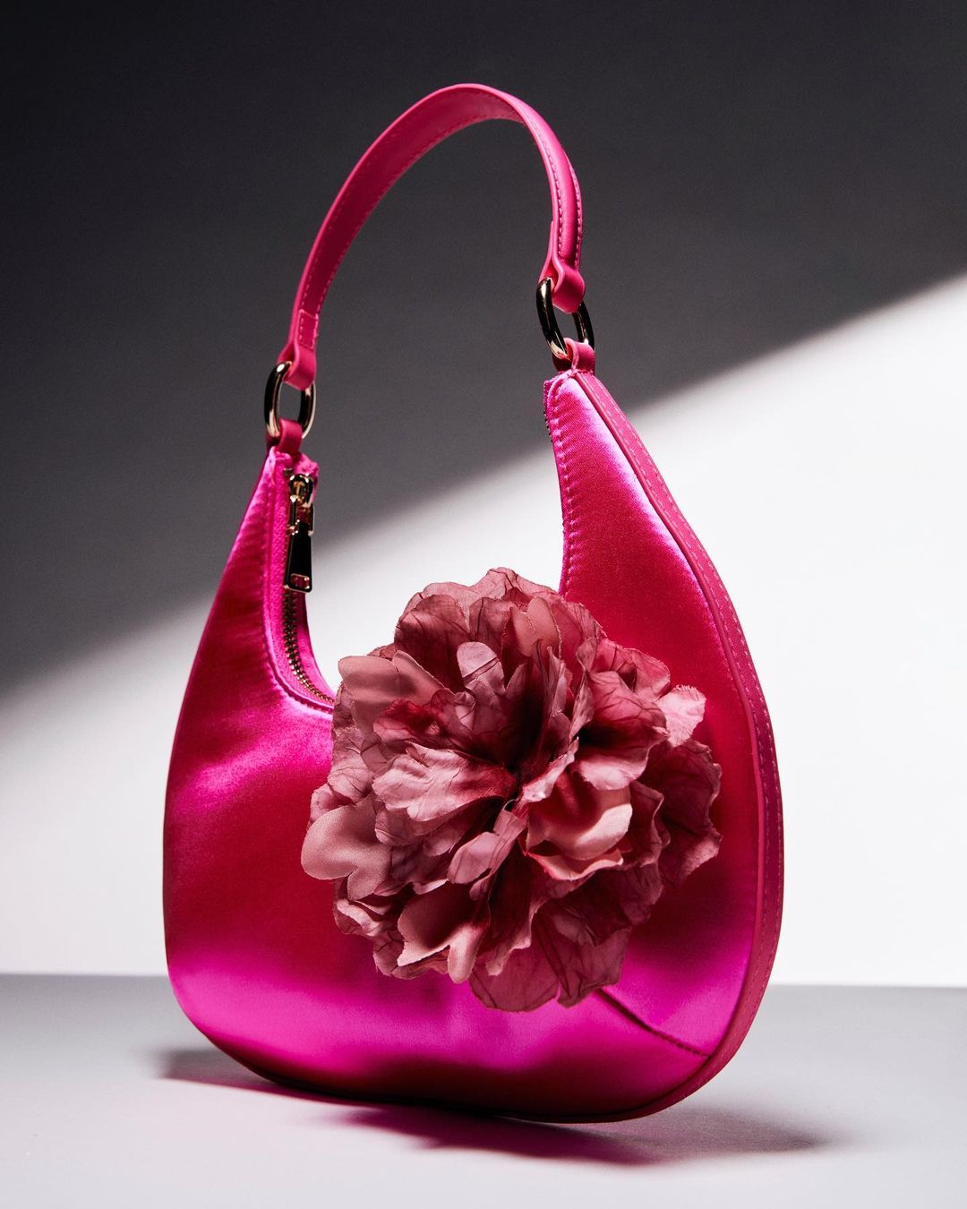 image of a satin fuschia handbag with a floral accent