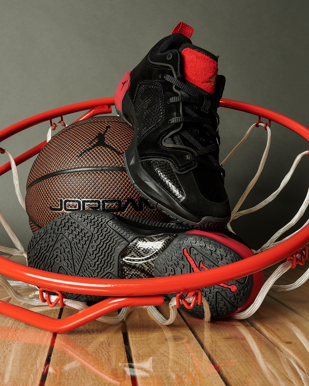 stylized image of a jordan basketball and black and red jordan sneakers in a basketball net placed on a wooden floor