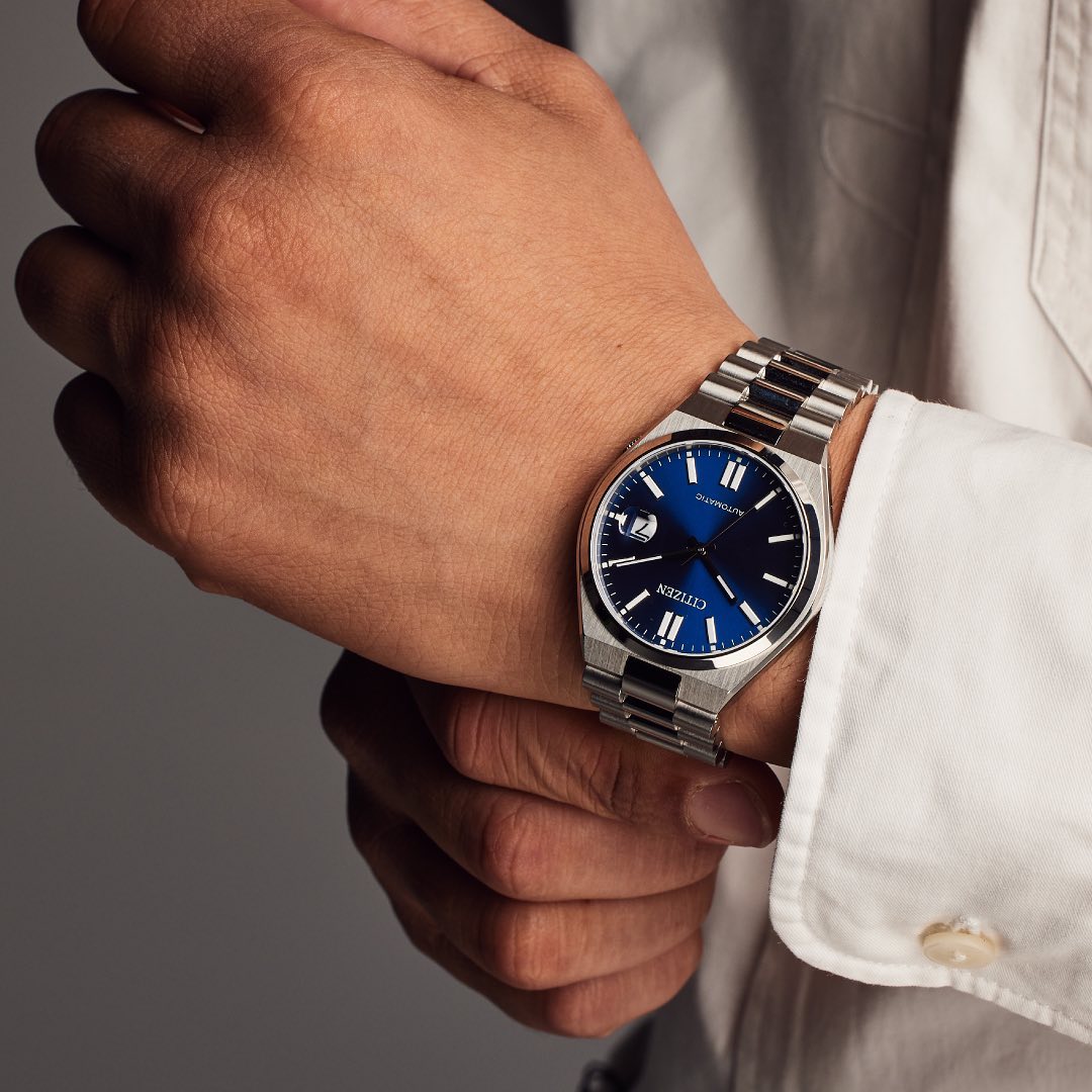 image of a man wearing a silver citizen watch with a blue watch face on his left wrist