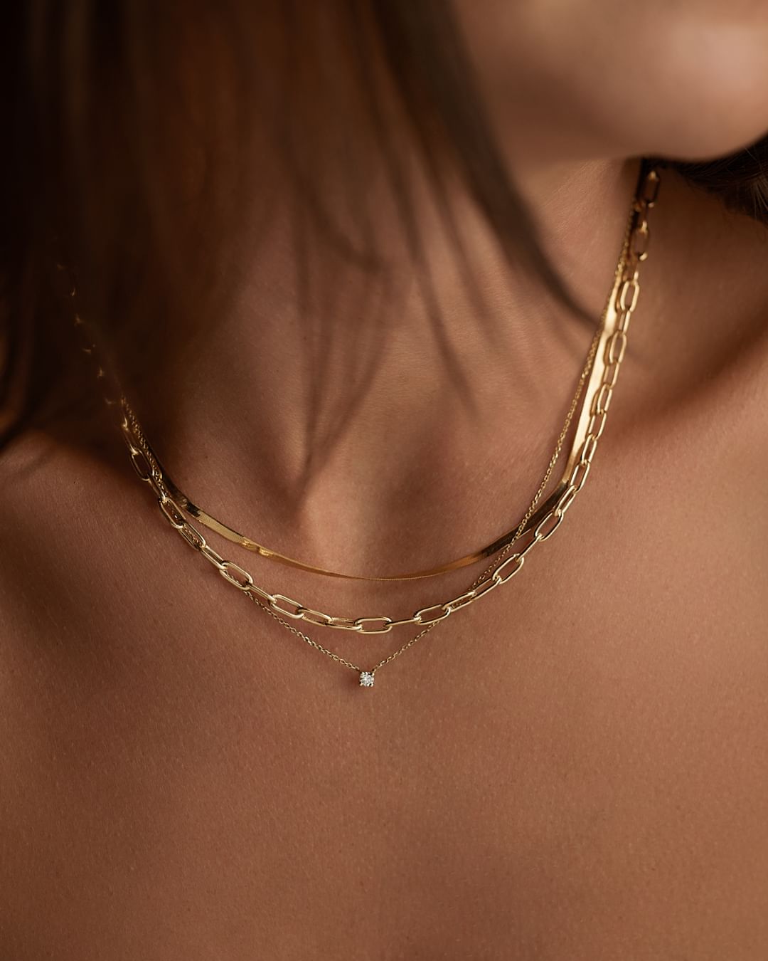 close up image of a model wearing layered gold necklaces
