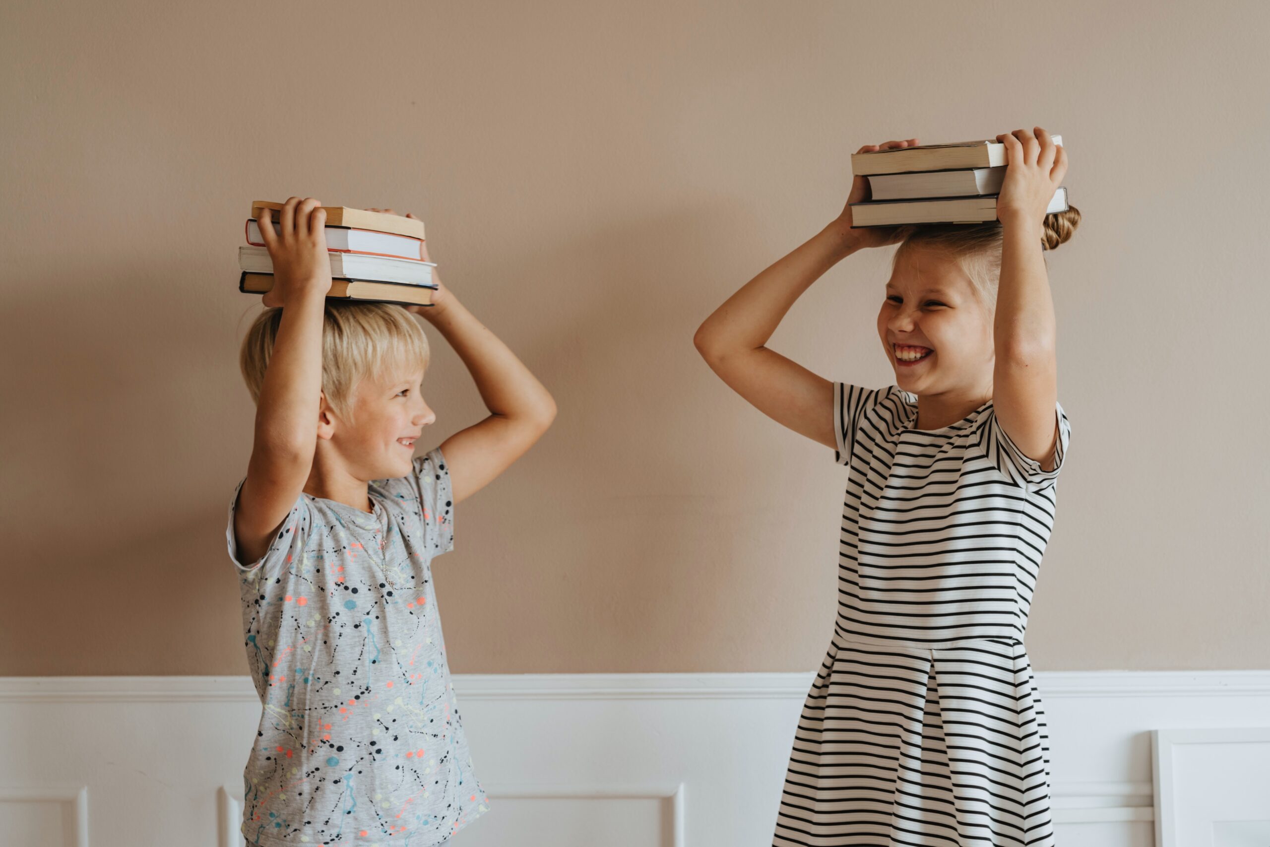 two kids holding books above their heads