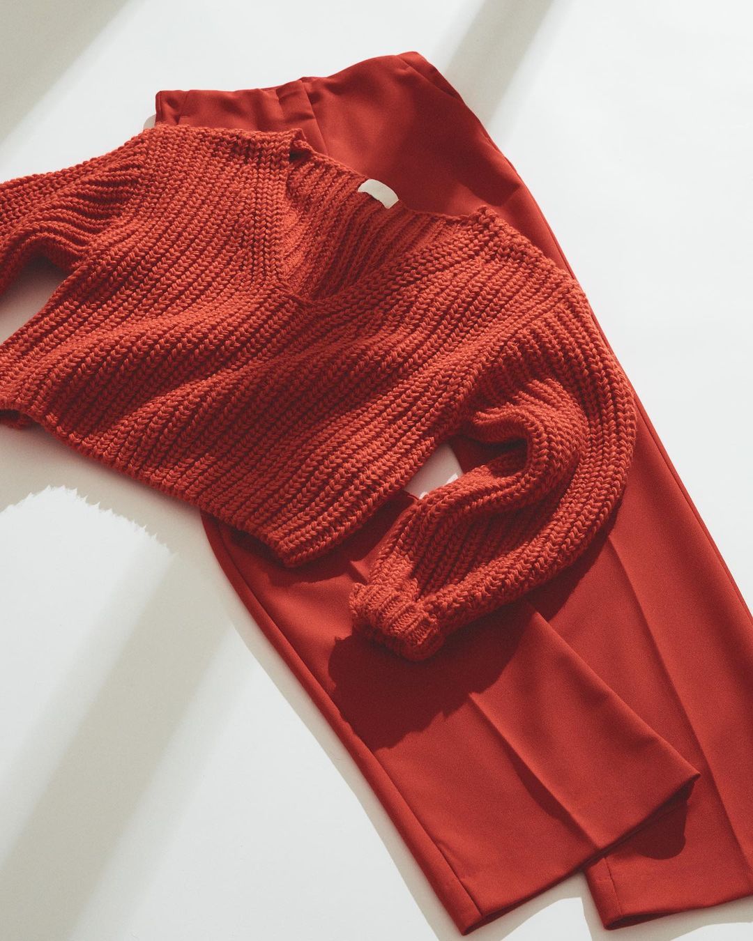 Red trousers with a red knit sweater laid over it.