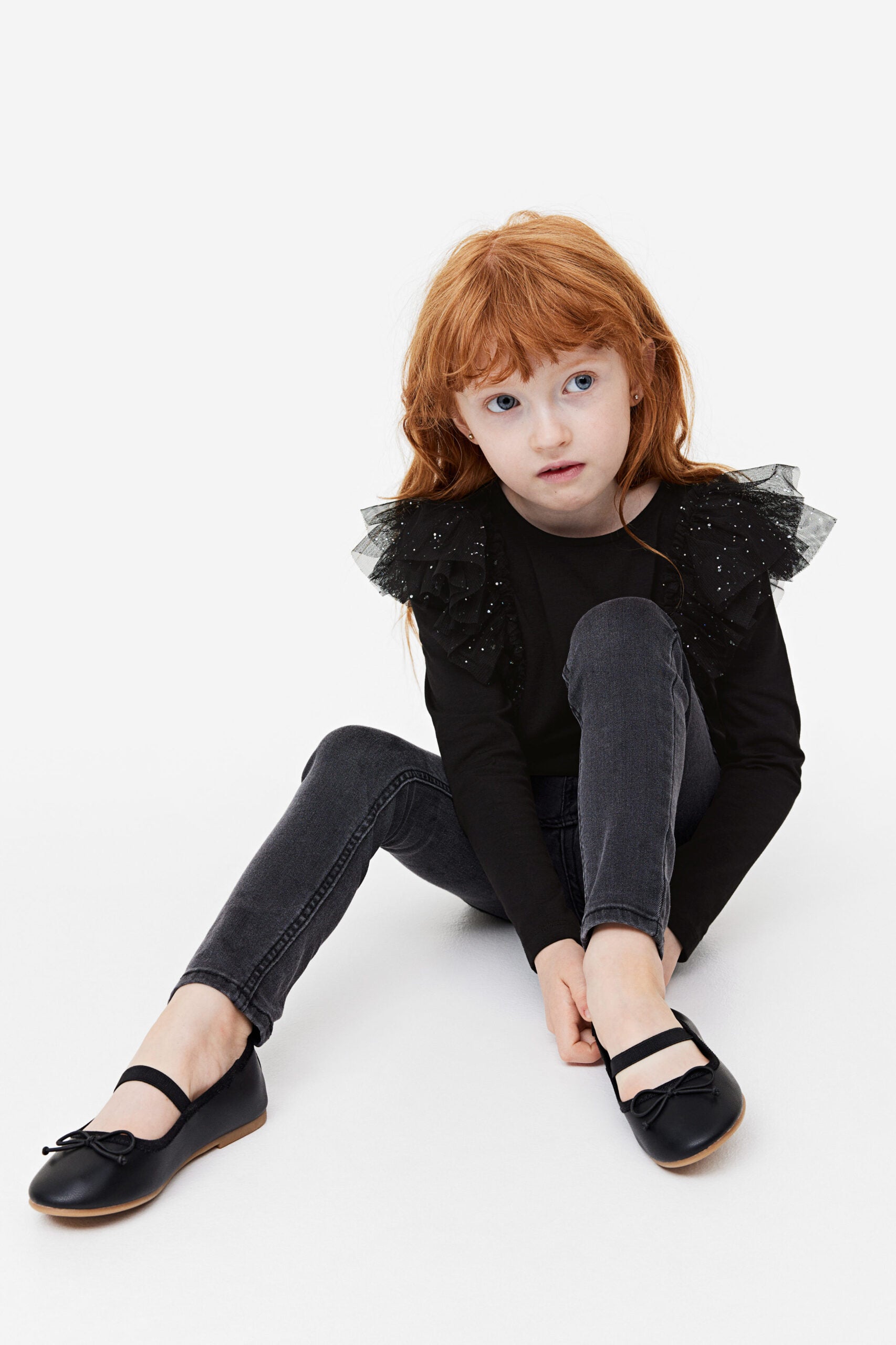 Girl wearing ruffled black shirt.