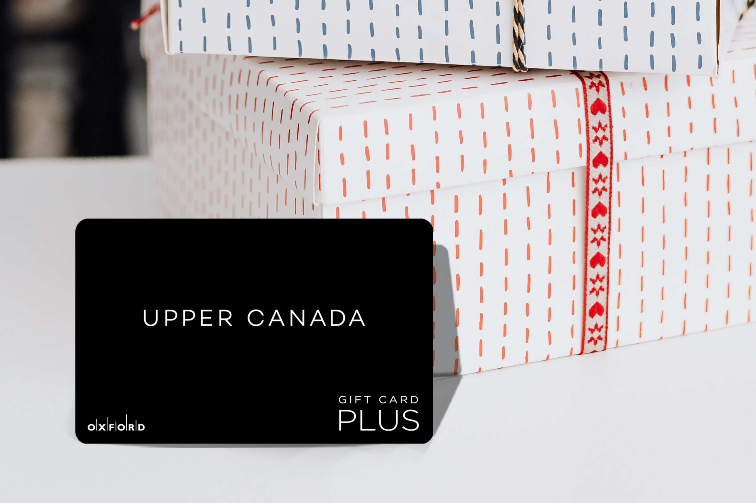 promotional image of a black UCM gift card in front of two gift boxes