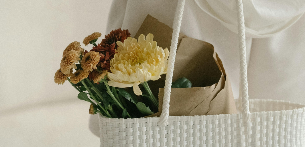 Woman holding white bag with flowers inside.
