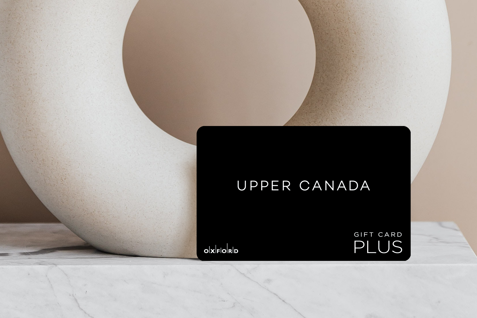 a promotional image of a black Upper Canada Mall gift card in front of a neutral ceramic circular vase