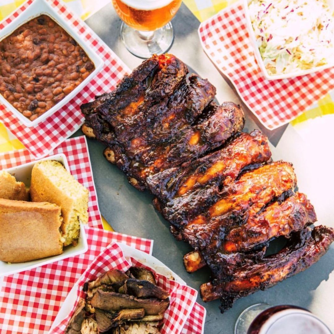 Ribs, baked beans, and more BBQ items on a picnic table
