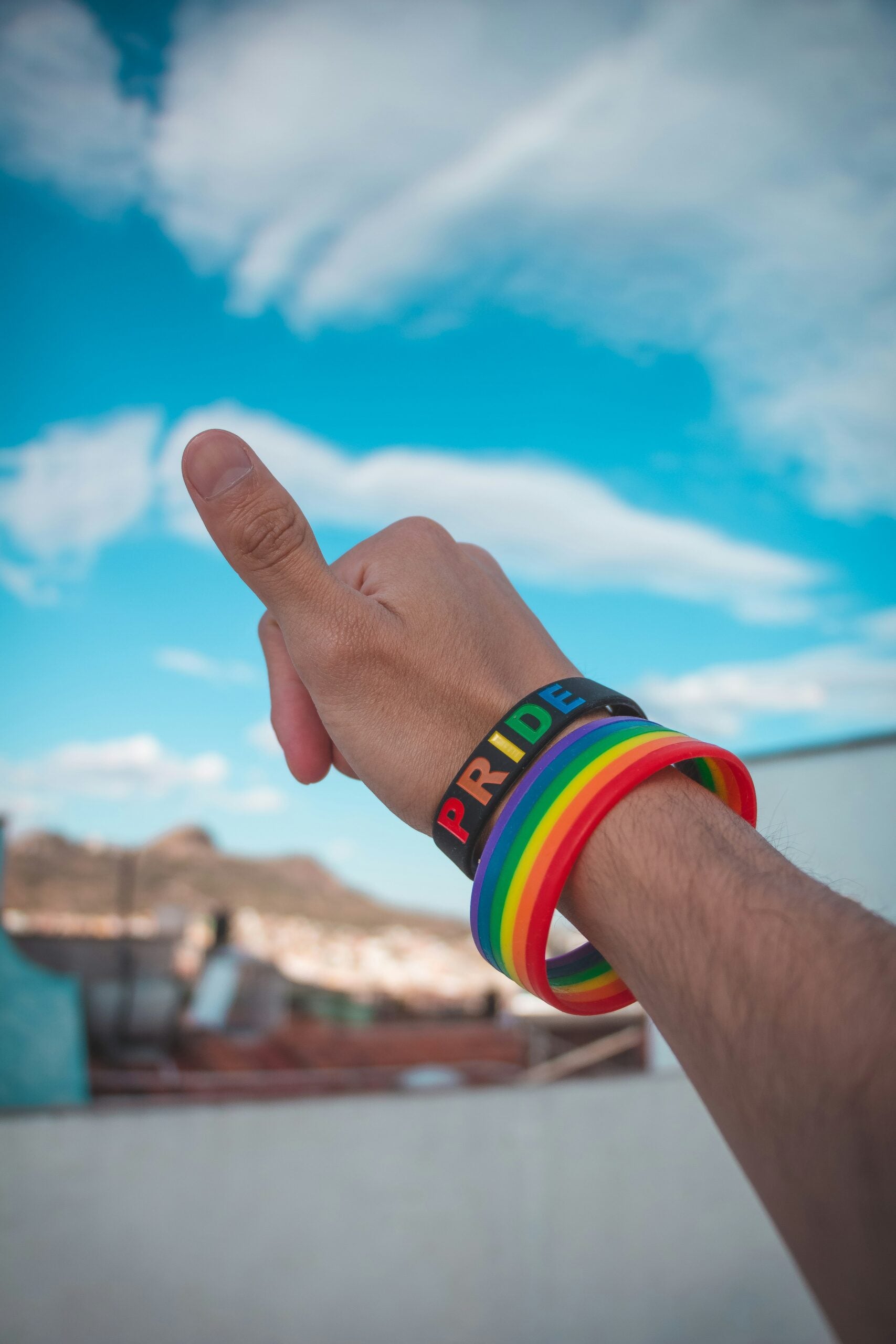 Person giving thumbs up with PRIDE bracelet