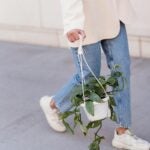 girl walking down the street in denim and cream blazer with a plant