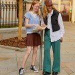 two girls standing at a bus stop laughing