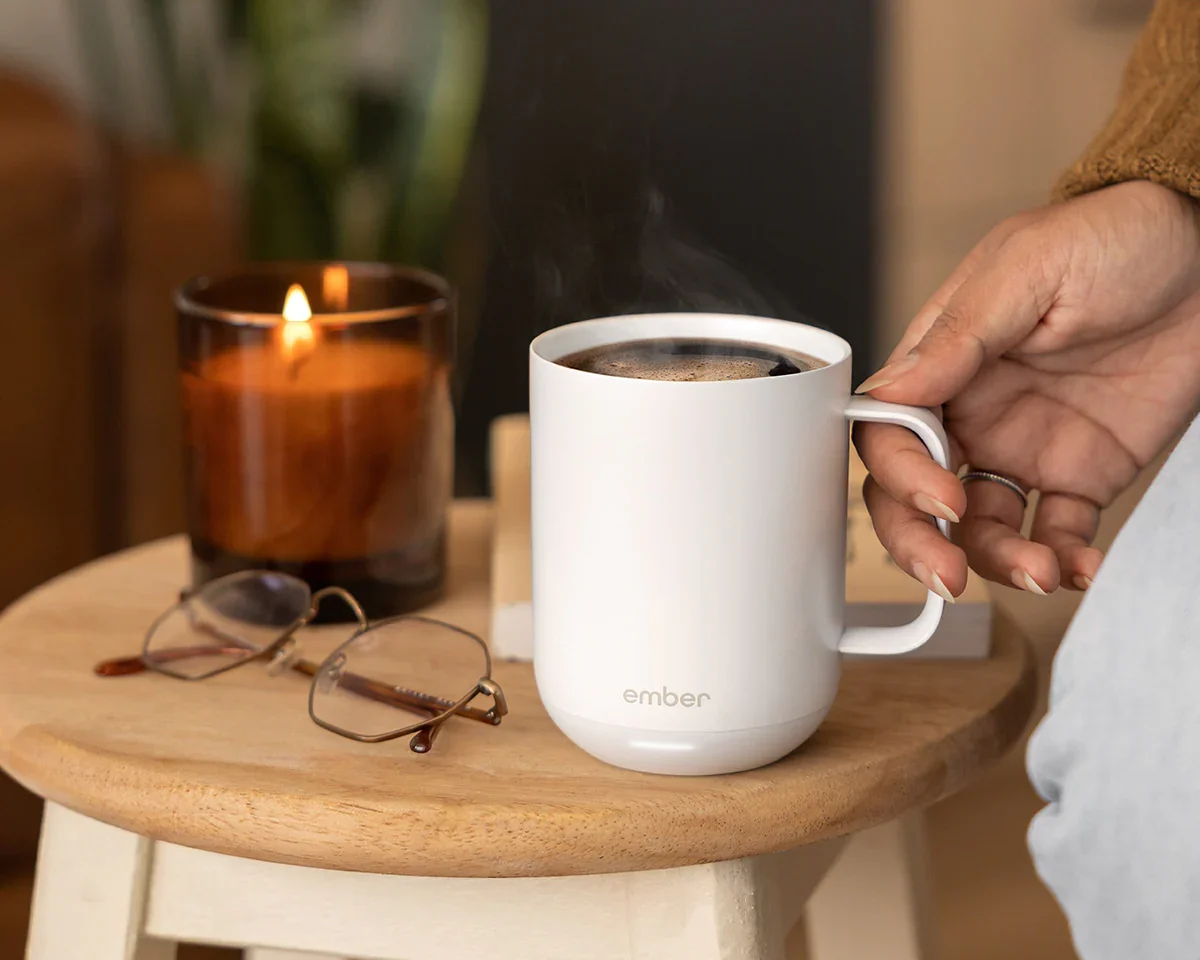 Mug on a side table with glasses and a lit candle