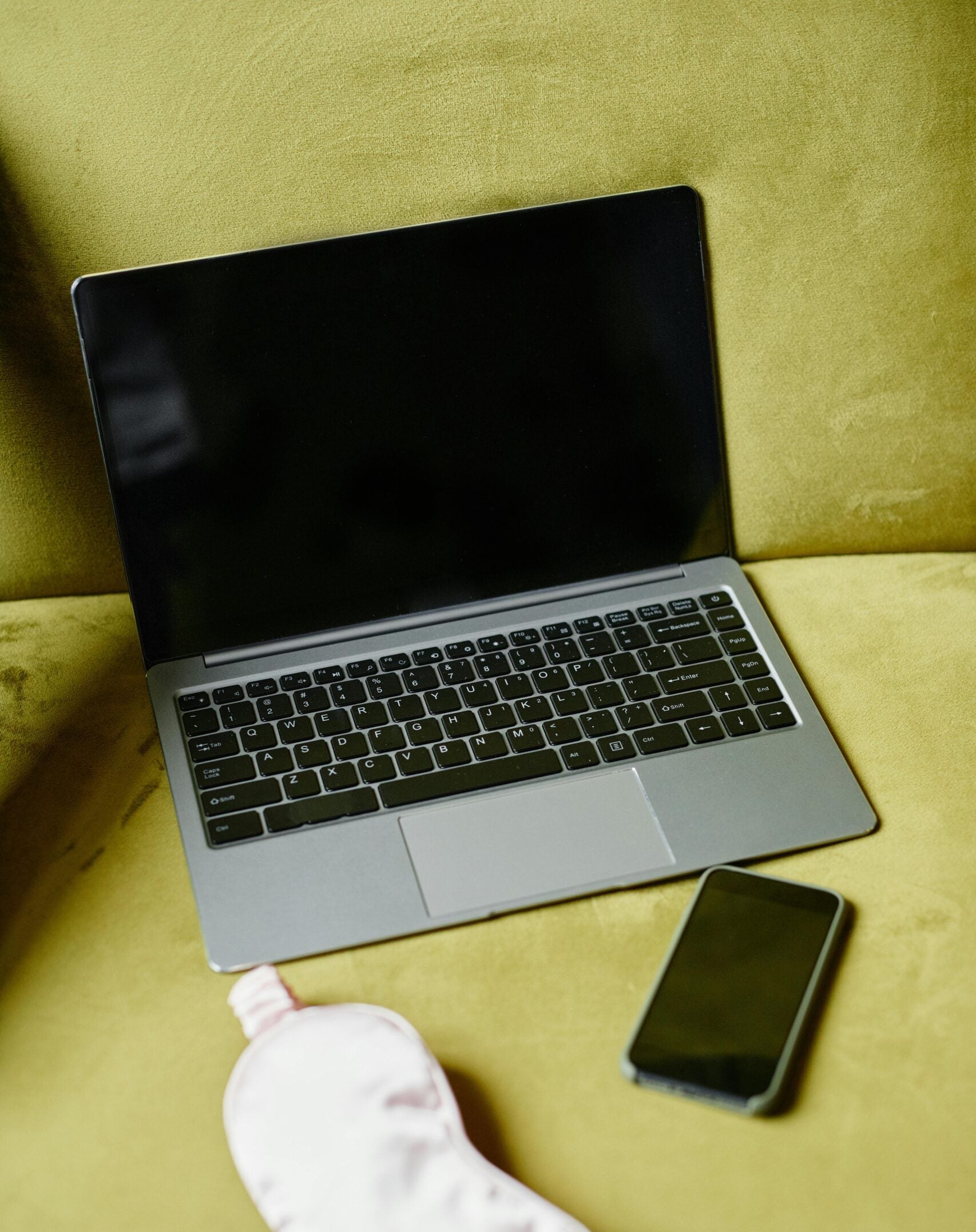 Laptop, phone, and eye mask on green background