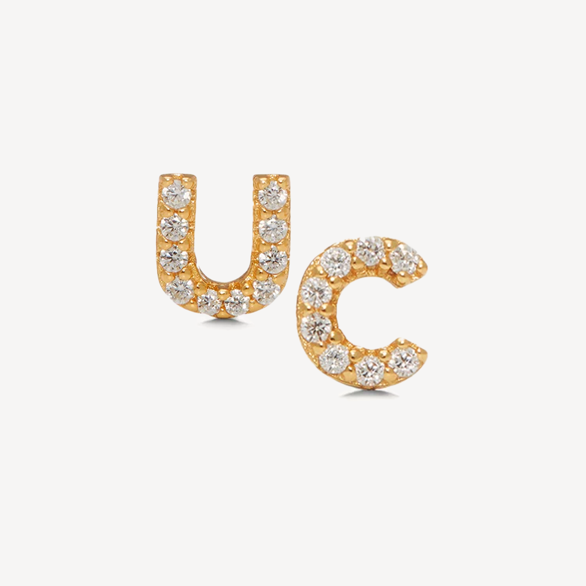 Gold jewellery with white crystals, in the shapes of letters U and C