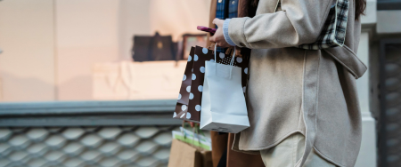 Woman and Man holding shopping bags outside of a store.